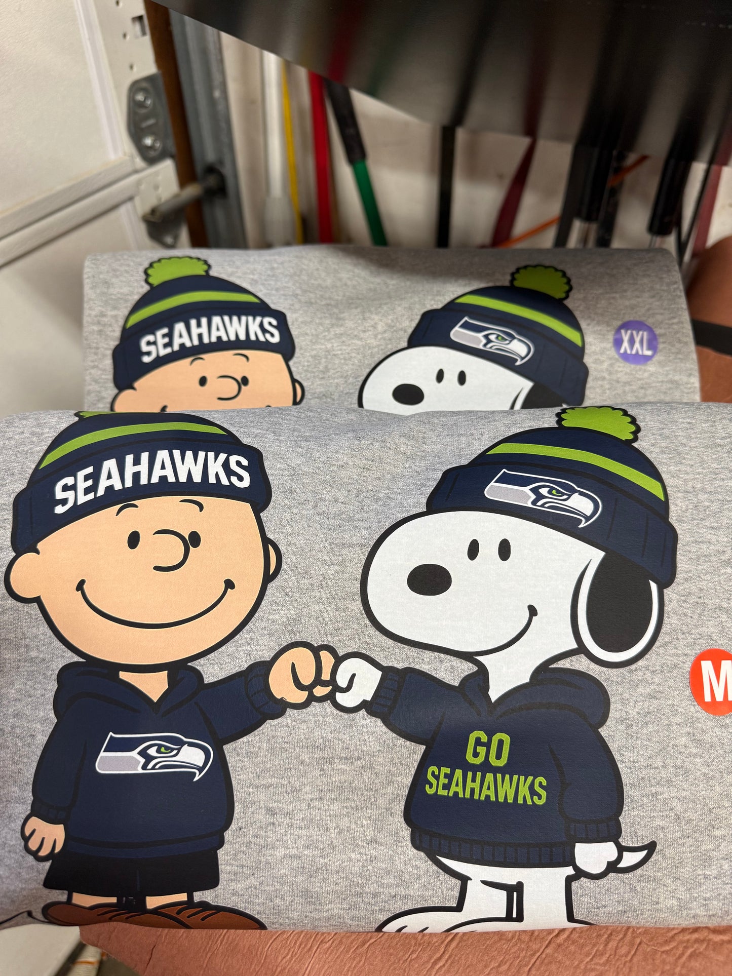 Gray sweatshirt with Snoopy and Woodstock wearing Seahawks hats and jerseys.