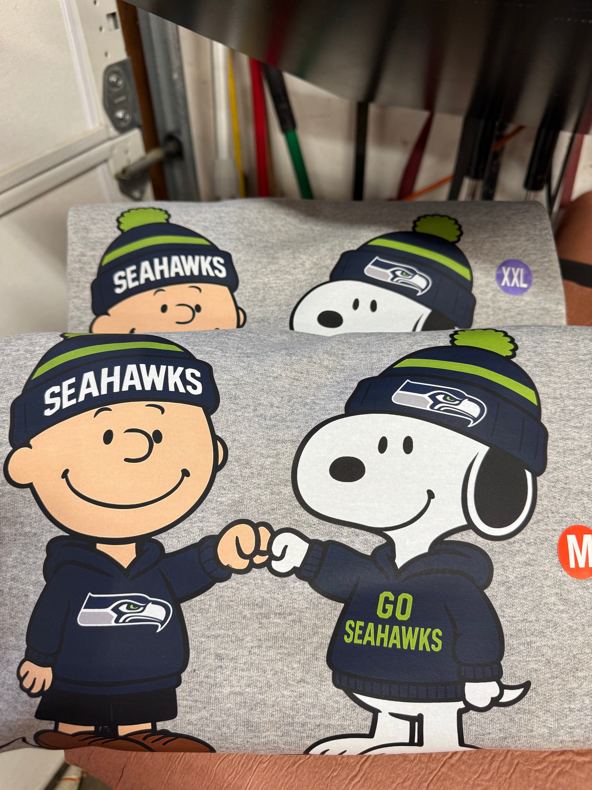 Gray sweatshirt with Snoopy and Woodstock wearing Seahawks hats and jerseys.