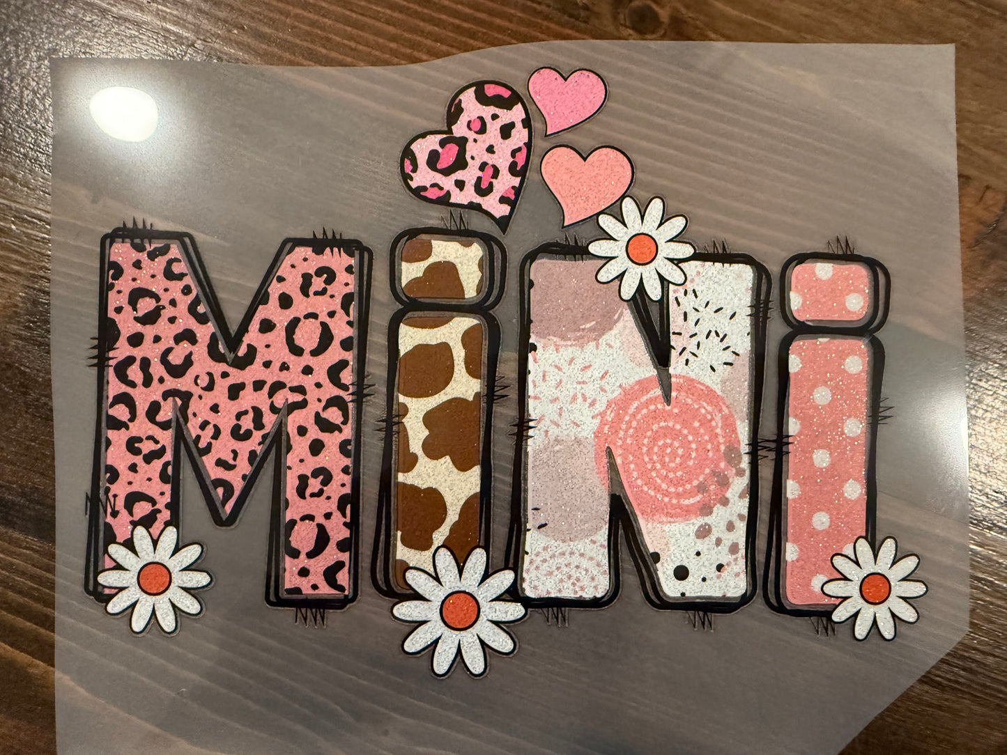 Decorative paper with the word 'Mini' in various patterns on a wooden surface