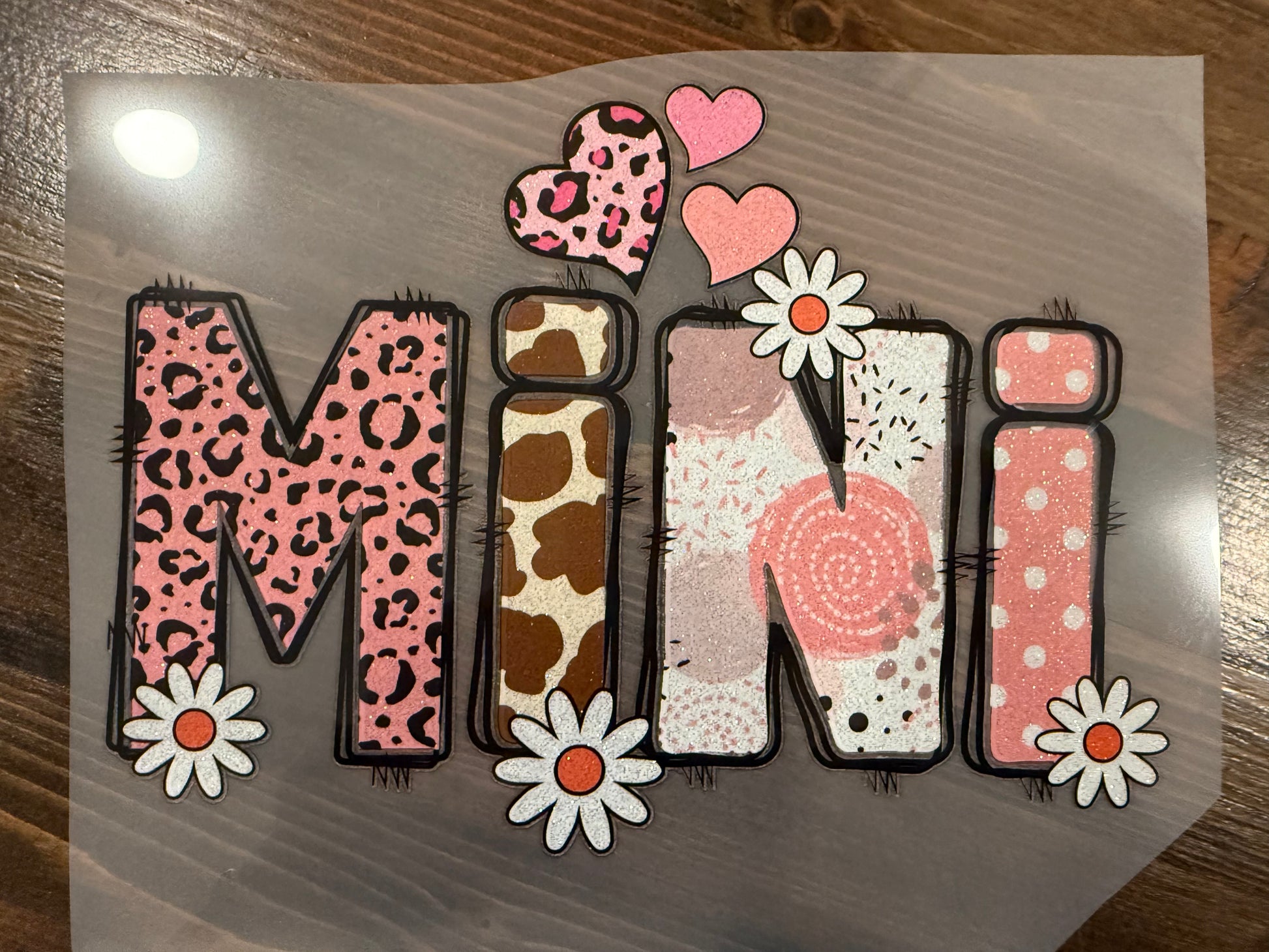Decorative paper with the word 'Mini' in various patterns on a wooden surface