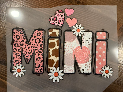 Decorative paper with the word 'Mini' in various patterns on a wooden surface