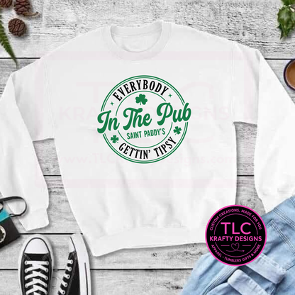 White sweatshirt with green text on a wooden surface, featuring the brand TLC Krafty Designs.