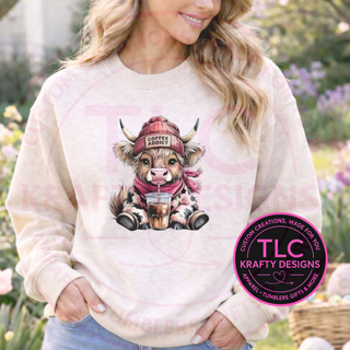 Person wearing a natural colored sweatshirt with a cow graphic and 'Coffee Addict' hat, standing outdoors.