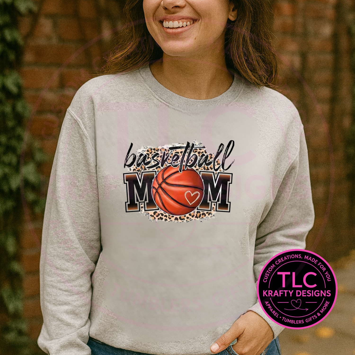 Person wearing a gray sweatshirt with 'Basketball Mom' design, standing outdoors.