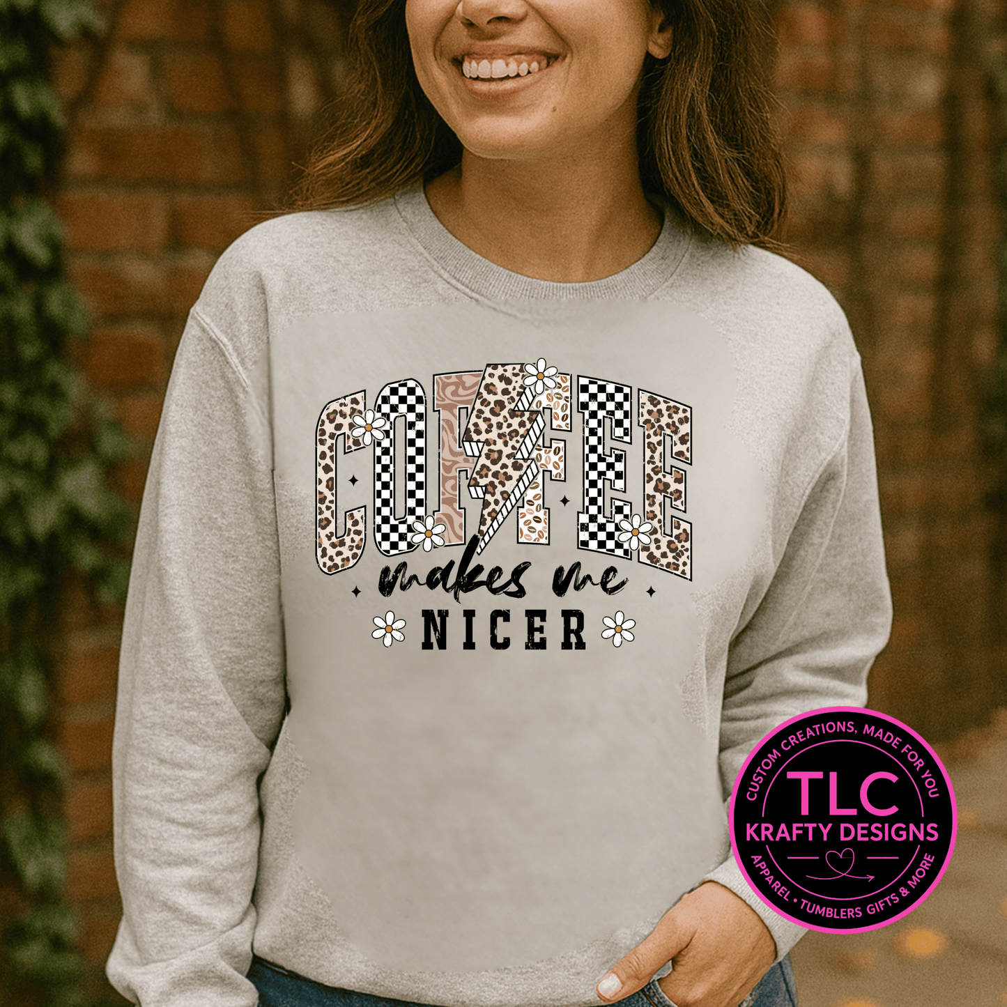 Person wearing a gray sweatshirt with a colorful graphic and text, standing against a brick wall.