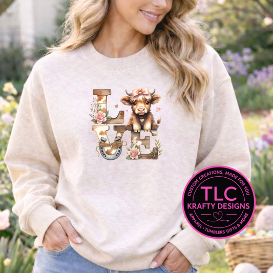 Person wearing a beige sweatshirt with a cow and 'LOVE' design, standing outdoors.