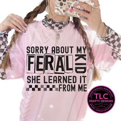 Person wearing a pink sweatshirt with sorry about my feral kid she gets it from me text and TLC Krafty Designs logo.