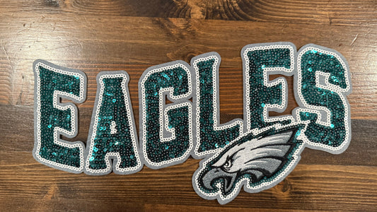 Glittery 'EAGLES' patch with a logo on a wooden background