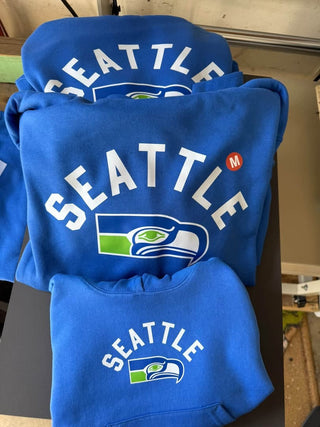 Seattle Football arch design on royal blue crewneck sweatshirt and youth hoodie